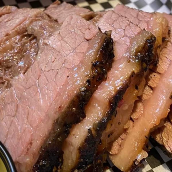 Close-up of Holy Smokes' sliced brisket with a dark, smoky bark and juicy pink interior.