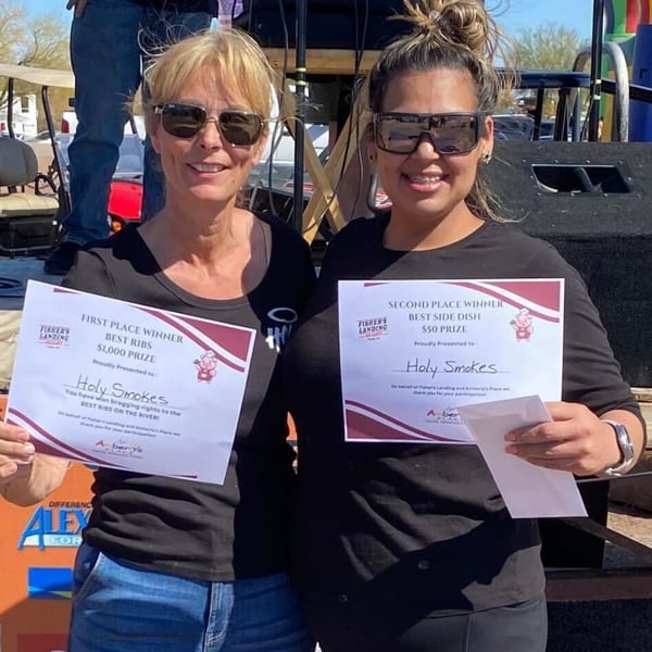 Two women from Holy Smokes proudly display their "Best Ribs" and "Best Side Dish" awards.