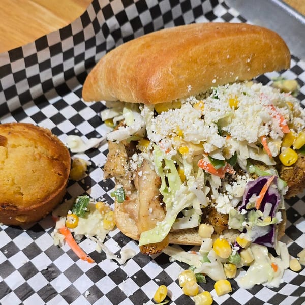 Holy Smokes BBQ sandwich with coleslaw, corn, and cheese, served with a cornbread muffin.